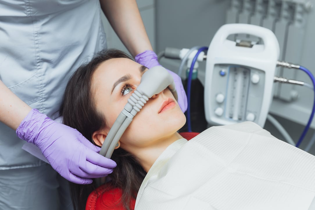 dentist puts inhalation sedative mask on his patient.